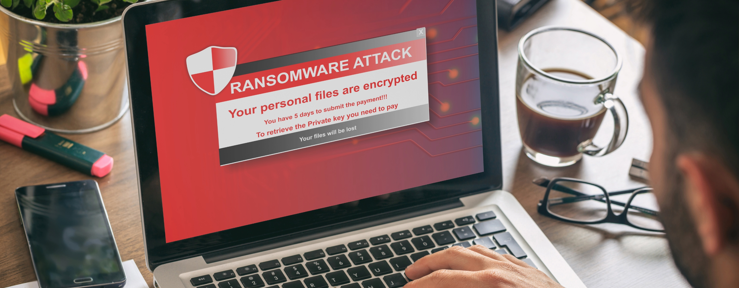Laptop screen showing ransomware attack alert with files encrypted message, representing cybersecurity threat.