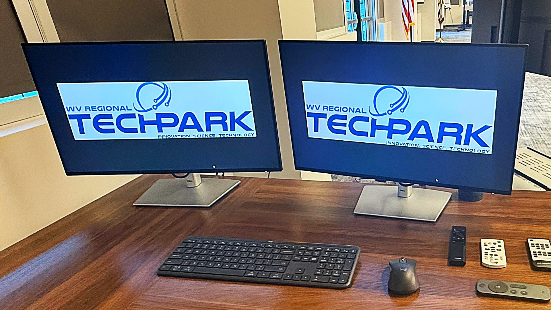 Dual desktop monitors displaying the WV Regional Technology Park logo as part of a professional conference center A/V upgrade in South Charleston, West Virginia.